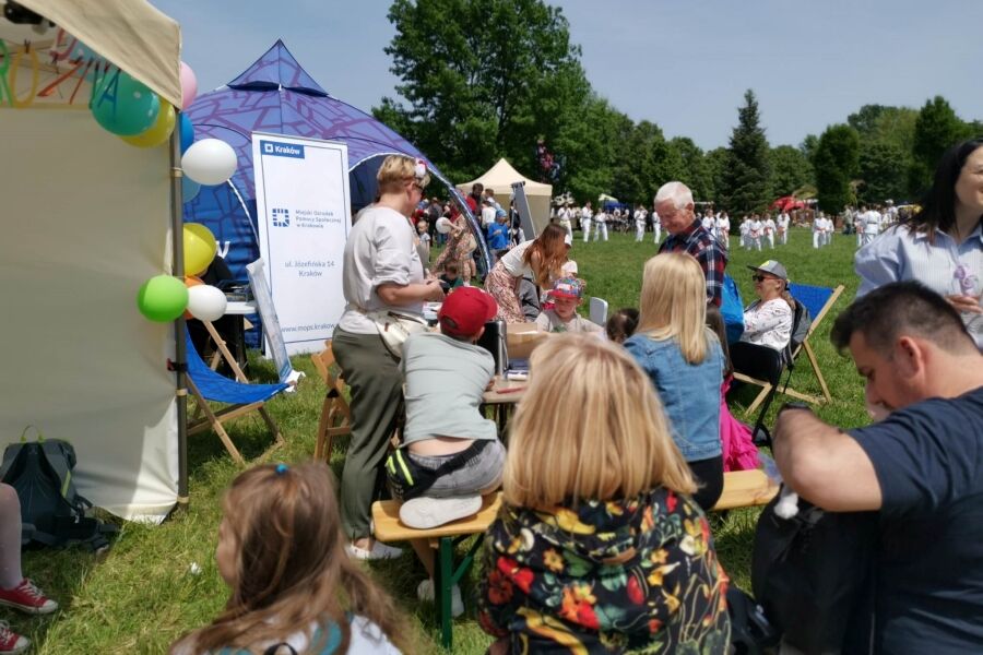 Rodziny uczestniczące w zabawach plenerowych, częściowo odbywających się w namiocie. 
