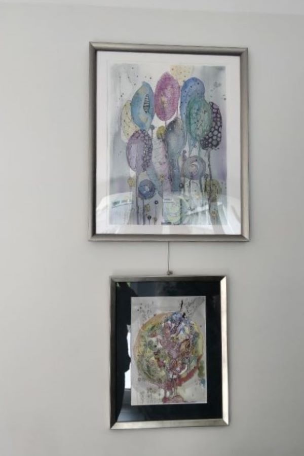 Obrazy w ramie na tle ściany, wiszące jeden pod drugim.