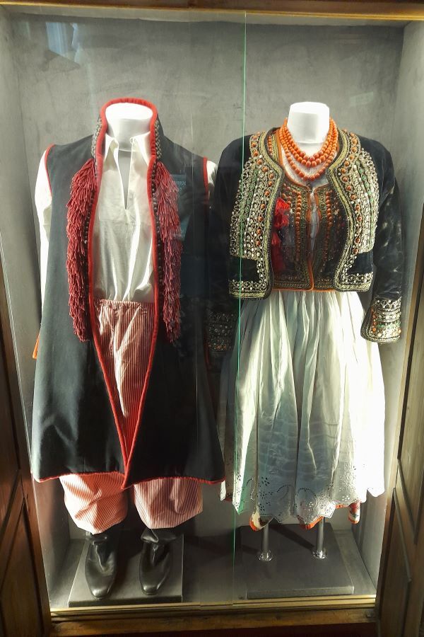 Umieszczone w szklanej gablocie stroje ludowe prezentowane na manekinach.