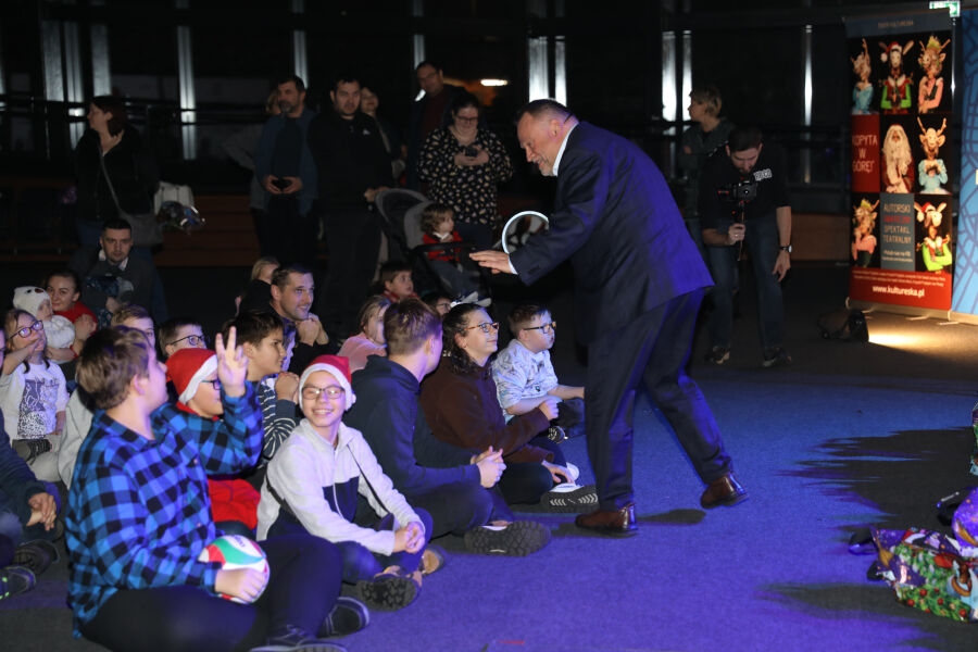 Zdjęcie przedstawia pana Andrzeja Kuliga rozdwajającego prezenty dzieciom z niepełnosprawnościami 