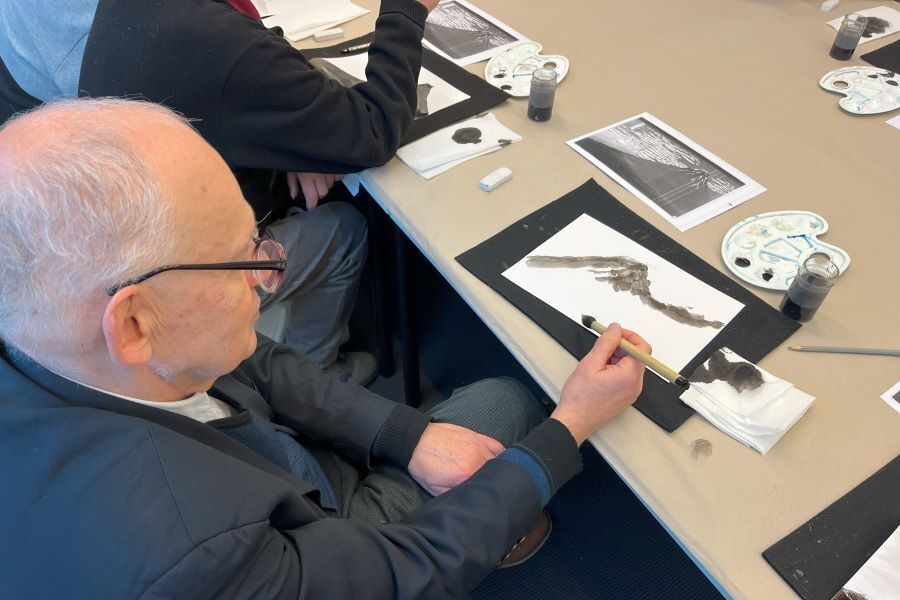 Uczestnik warsztatów maluje obraz przy użyciu tuszu japońskiego