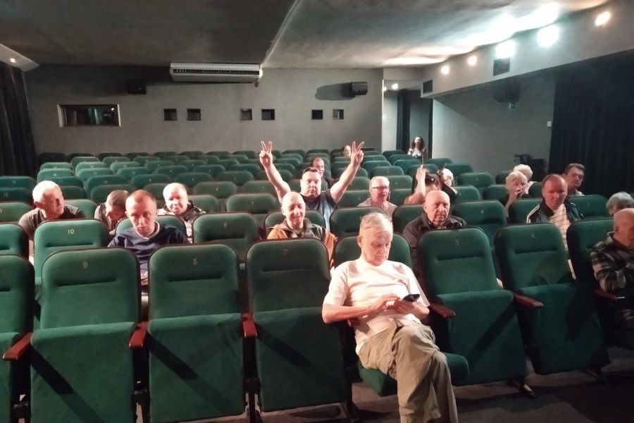 Grupa kobiet i mężczyzn siedzących na fotelach w sali kinowej.
