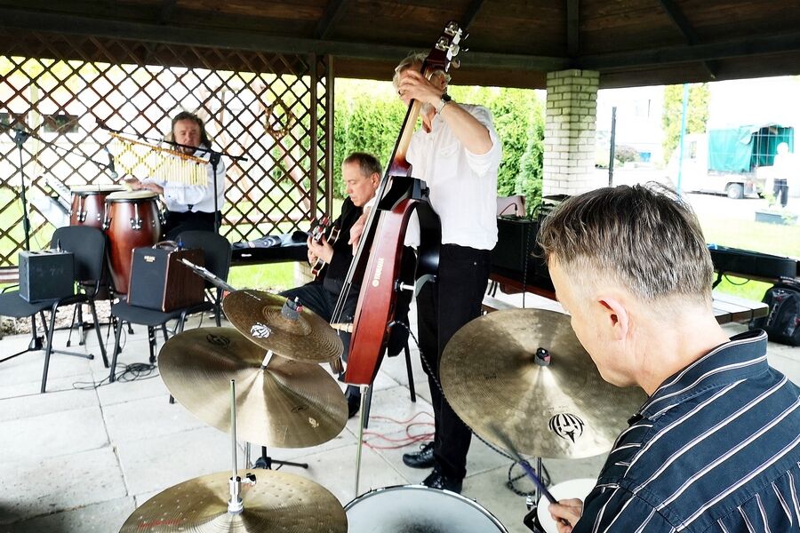 Czterech muzyków grających na instrumentach: perkusji, kontrabasie, gitarze i kongach