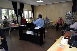 Muzykoterapia 22.04.2024 Mieszkańcy siedzą w kręgu przed terapeutą.