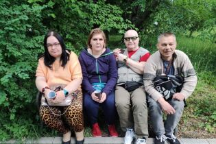 Zaczarowany Dzień w Ogrodzie Botanicznym Dwie kobiety i dwóch mężczyzn siedzących na ławce w plenerze na tle roślin.