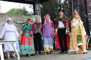 Spotkanie z okazji Dnia Matki i Dnia Dziecka Grupa kobiet i mężczyzn występujących na scenie plenerowej.