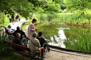 Ogród Botaniczny 08.07.2024 Kilkoro mieszkańców siedzi nad stawem.