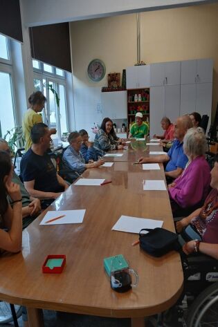 Kalambury 05.08.2024 Mieszkańcy siedzą zgromadzeni w sali terapii. Rozwiązują zagadki.