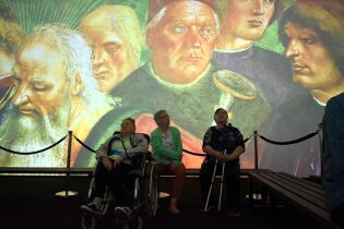 Wystawa 27.08.2024 Trzy mieszkanki na tle wyświetlonych na całą ścianę fresków z Kaplicy Sykstyńskiej.
