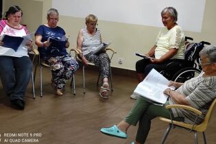 Spotkanie ze sceną 04.08.2024 Pięć mieszkanek siedzi w kręgu, trzymają na kolanach duże kartki