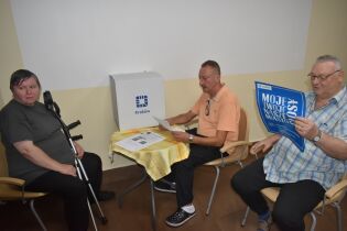 Budżet Obywatelski 2024 13.09.2024 Troje mieszkańców siedzi na krzesłach przegląda materiały wyborcze.