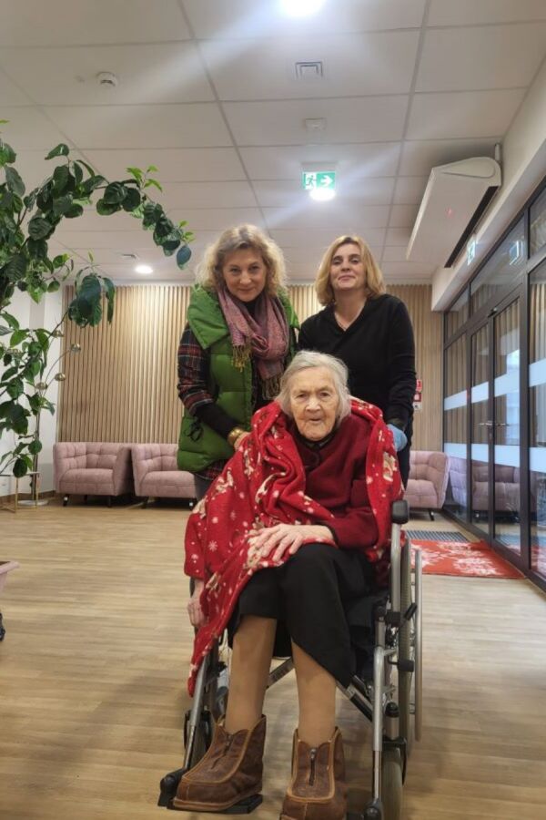 Dyrekcja, mieszkanka oraz pracownik Domu uśmiechają się w holu budynku DPS przy ul. Praskiej 27.