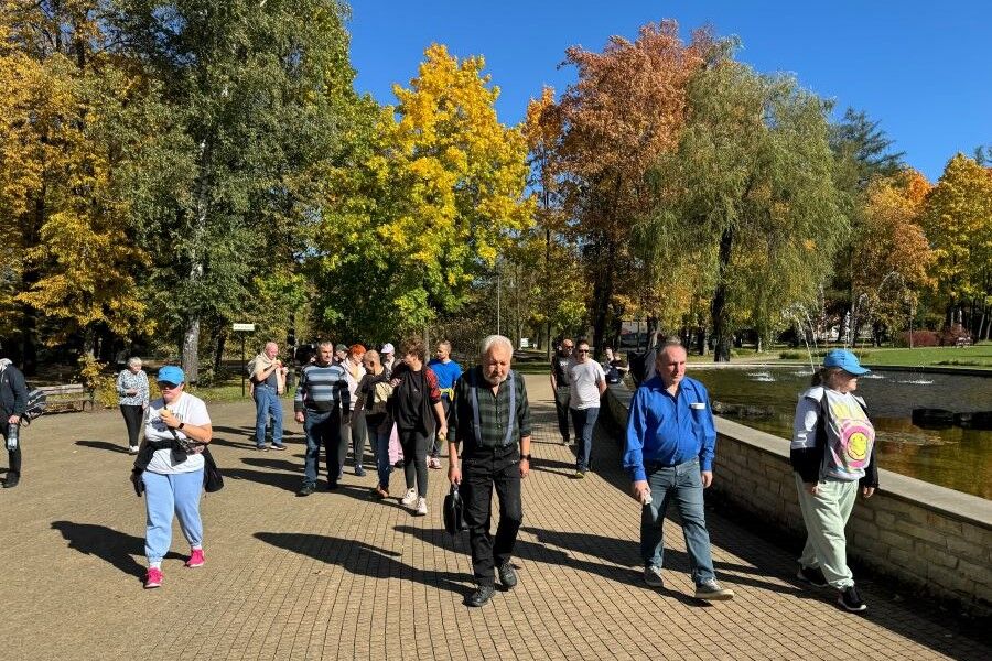 Grupa kobiet i mężczyzn na tle architektury drewnianej.