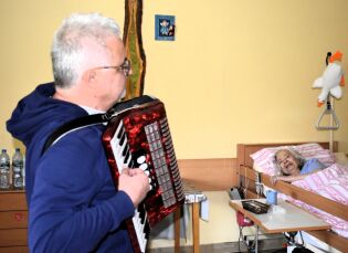 „Gość w Dom” 25.11.2024 Mieszkanka leży w łóżku, słucha akordeonisty.