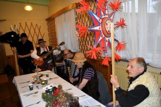 Spotkanie opłatkowe 14.12.2024 Kilku mieszkańców przebranych za pastuszków, trzymają gwiazdę i Turonia, terapeuta w stroju góralskim gra na gitarze wolontariusz na akordeonie.