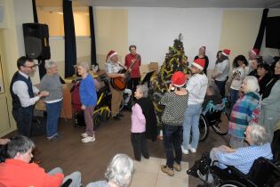 Cosinus Kraków 16.12.2024 Kilkudziesięciu mieszkańców i słuchaczy stoi wokół choinek.
