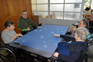Stół terapeutyczny 17.02.2025 Czworo mieszkańców siedzi przy dużym stole.