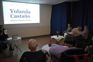 Spotkanie z poezją 12.03.2025 Kilkunastu mieszkańców przed ekranem, prowadząca trzyma mikrofon.
