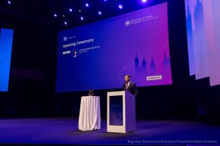 Wolność słowa i nowe wyzwania dziennikarstwa – globalni liderzy mediów obradują w Krakowie Prezydent Krakowa Aleksander Miszalski przemawia podczas ceremonii otwarcia Światowego Kongresu Mediów Informacyjnych. Po lewej stronie ekran na którym na granatowym tle wyświetla się nazwisko Prezydenta Krakowa. Po prawej mównica.
