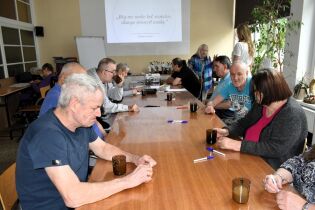 Zajęcia poznawcze 26.05.2025 Kilkunastu mieszkańców siedzi przy długim stole.