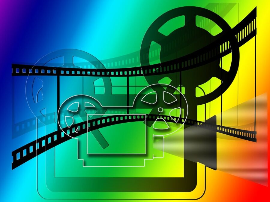 Grafika. na tęczowym tle schematycznie przedstawiony duży projektor kinowy powyżej taśma filmowa.