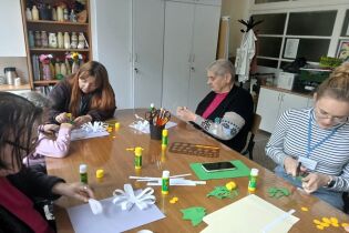 Arteterapia 30.05.2025 Mieszkańcy i terapeuci wycinają kwiaty z papieru.