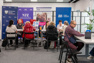 Zdjęcie przedstawia pracowników Punktu Informacyjnego dla Obcokrajowców podczas udzielanie informacji interesantom we wnętrzu biura