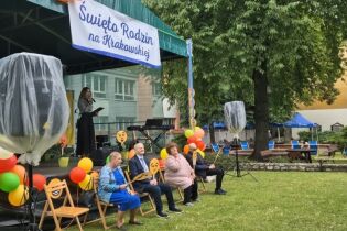 Kilka osób siedzących na krzesłach przed sceną