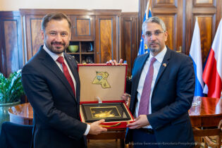 Wizyta Ambasadora Kuwejtu Wizyta Ambasadora Kuwejtu u Prezydenta Krakowa 10.06.25. Na zdjęciu Prezydent Aleksander Miszalski i Ambasador . Saad Abdulazizi Mohammad Al–Mehaini pozują trzymając otwartą kasetę z plakietą statku.