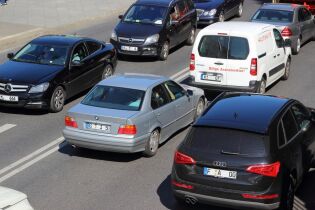 Ruch drogowy w mieście. Na zdjęciu widoczna dwupasmowa jezdnia i kilkanaście aut różnych marek z niemieckimi nr rejestracyjnymi w ruchu ulicznym. W górnym lewym rogu widoczny szeroki chodnik. 