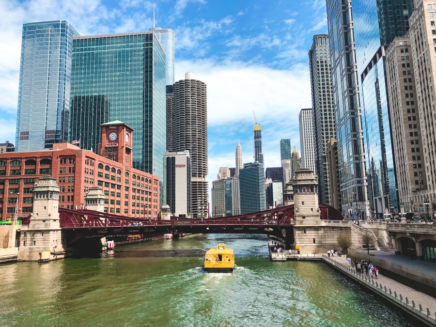 Krajobraz Chicago - wysokie wieżowce, rzeka i łódka z turystami.