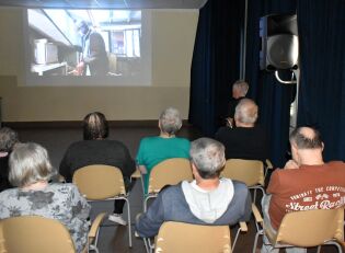 Domowe kino 15.07.2025 Grupa osób ogląda film wyświetlany na ekranie w ciemnym pomieszczeniu.