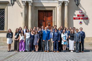 Wizyta belgijskiego Stowarzyszenia Akademickiego w krakowskim magistracie. Zdjęcie grupowe dużej grupy osób przed wejściem paradnym do Pałacu Wielopolskich. 