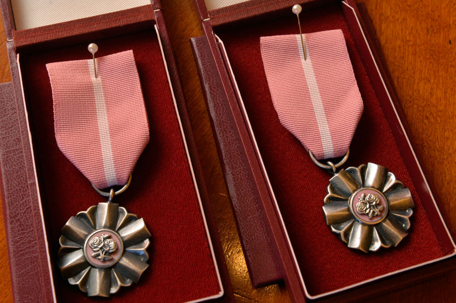 Zdjęcie przedstawia dwa Medale za Długoletnie Pożycie Małżeńskie. Dwa srebrne medale na różowych wstążkach, leżące w pudełkach z czerwonym, aksamitnym wnętrzem. 