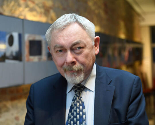 Jacek Majchrowski były prezydent Miasta Krakowa. Zbliżenie głowy. W tle wystawa artystyczna. 