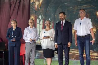 pięć osób stojących na scenie. w Tle scenografia imitująca średniowieczny zamek