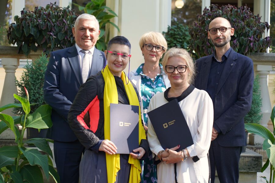 Uroczystość podpisania kolejnej umowy o współpracy Biblioteki Kraków z Biblioteką Miejską w Zagrzebiu. Na fotografii na schodach w pierwszym rzędzie stoją dyrektorki obu instytucji trzymając umowy.