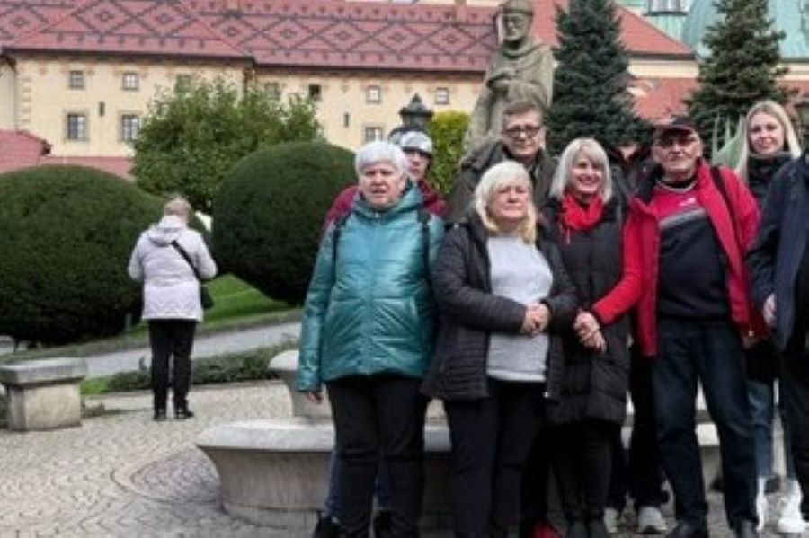 grupa osób stoi na tle klasztoru