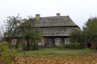 Grafika przedstawia stary budynek w otoczeniu drzew.