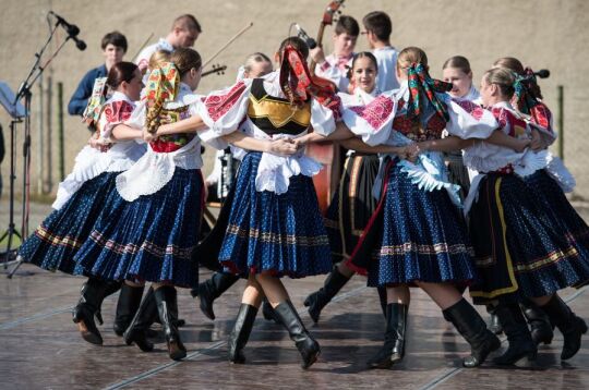 Grafika przedstawia zespół taneczny podczas wystepu na scenie.