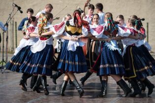 Grafika przedstawia zespół taneczny podczas wystepu na scenie.