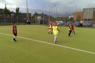 Grafika przedstawia dzieci grające w piłkę na boisku.