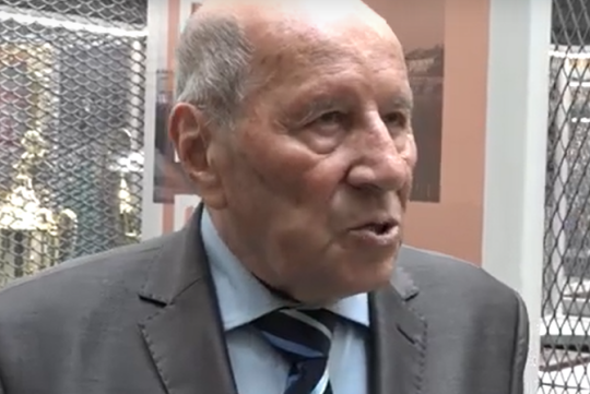 na zdjęciu jest Ludwik Miętta-Mikołajewicz. Duże zbliżenie twarzy mężczyzny który coś mówi.  