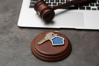 Na grafice widnieje młotek sędziowski i klucze, sugerujące licytacje lokalu