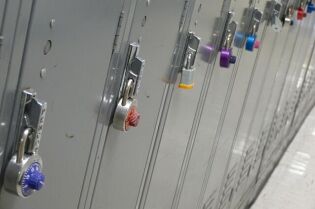 Grafika przedstawia rząd szafek w kolorze szarym zamkniętych na klódki. 