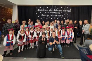 grupa kilkudziesięciu osób stoi w czterech rzędach. Z przodu dzieci w krakowskich strojach