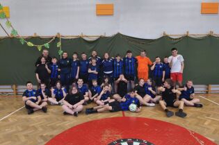 Projekt Inter Campus w Krakowie. Zdjęcie grupowe kilkunastu młodych osób oraz kilkorga dorosłych. Stoją w dwóch rzędach po drabinkami w sali gimnastycznej w koszulkach sportowych. 