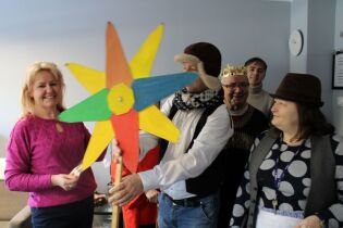 Uśmiechnięci kolędnicy pozują do wspólnego zdjęcia, jeden z nich trzyma kolorową gwiazdę kolędniczą. 