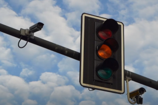 Na tle niebieskiego nieba sygnalizator świateł z wyświetlonym czerwonym światłem dla samochodów.