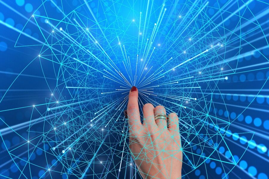 Grafika komputerowa. Dłoń kobiety i jej palec wskazujący na tle promieniście rozchodzących się schematycznie przedstawionych impulsów mających prezentować działanie sieci komputerowej.  